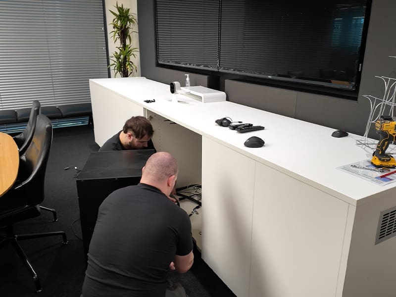 man sitting at a desk in front of a tv